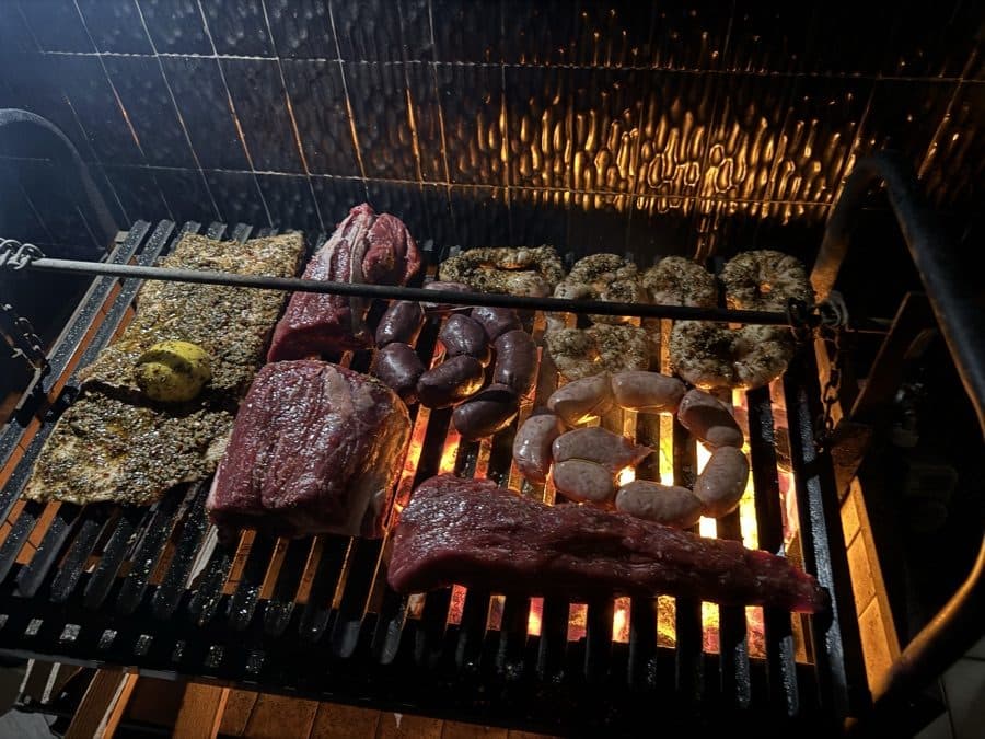 An asado loaded on the grill over glowing coals